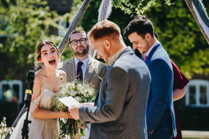 bride roar with laughter while friend gives speech at ceremony. Family farm in Hildenborough, Kent.