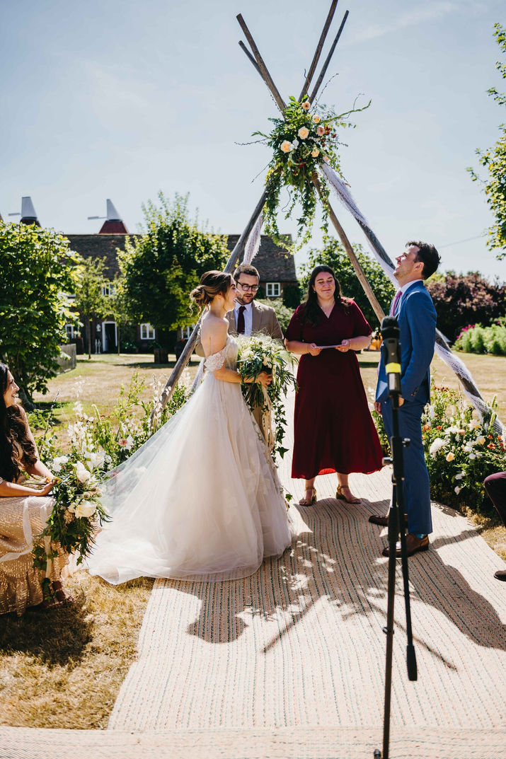 groom and bride face to face with two registrars in the background. Family farm in Hildenborough, Kent.