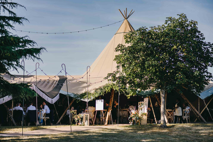 people enjoying the wedding breakfast under the marquees. Wedding in a family farm. Hildenborough, Kent.