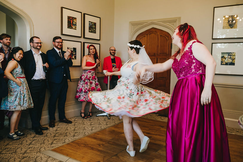 Bride twirling while holding the other bride’s hand just before the wedding ceremony at Hartsfield Manor Hotel, Betchworth.