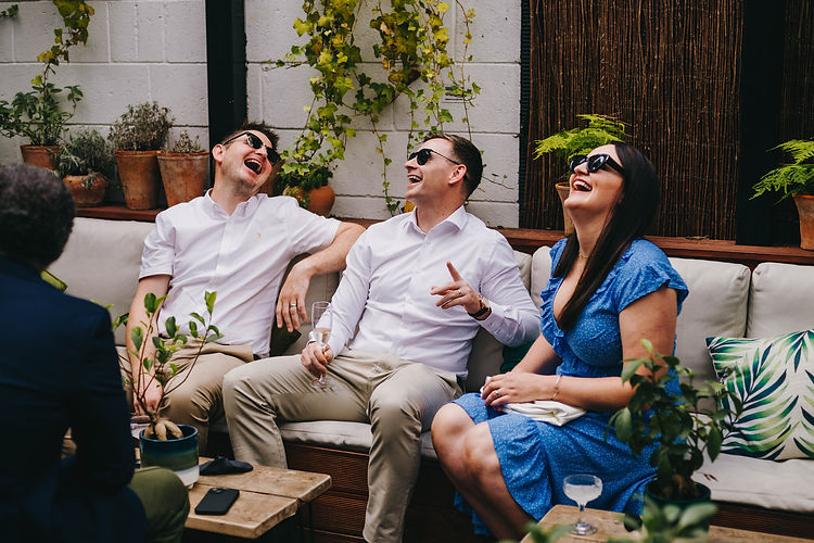 Just three friends laughing and sitting on a couch at The Hackney.
