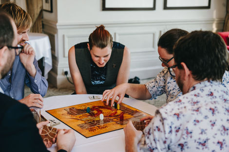 Guest making a move on a game of Tsuro. Lesbian wedding at Hartsfield Manor Hotel, Betchworth.