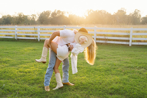 a couple kissing behind her cowboy hat while he dips her during Baton Rouge engagement session 