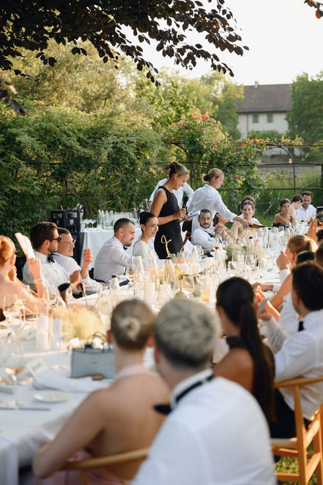 Brautpaar und Hochzeitsgäste geniessen einen festlichen Empfang bei einer Sommerhochzeit im Freien
