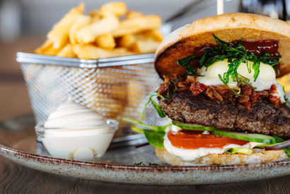 Saftiger Rindfleischburger mit geschmolzenem Käse und Salat, serviert mit knusprigen Pommes frites und Mayonnaise auf einem Teller.