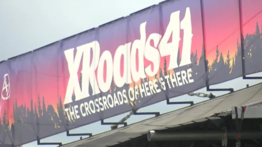 Banner with "XRoads41 The Crossroads of Here & There" text, featuring a sunset silhouette of trees, hangs above a roofline.