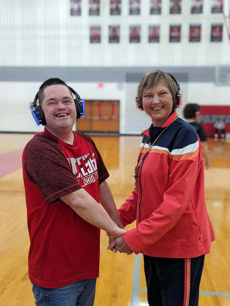 Two people dancing while holdings hands with headphones on
