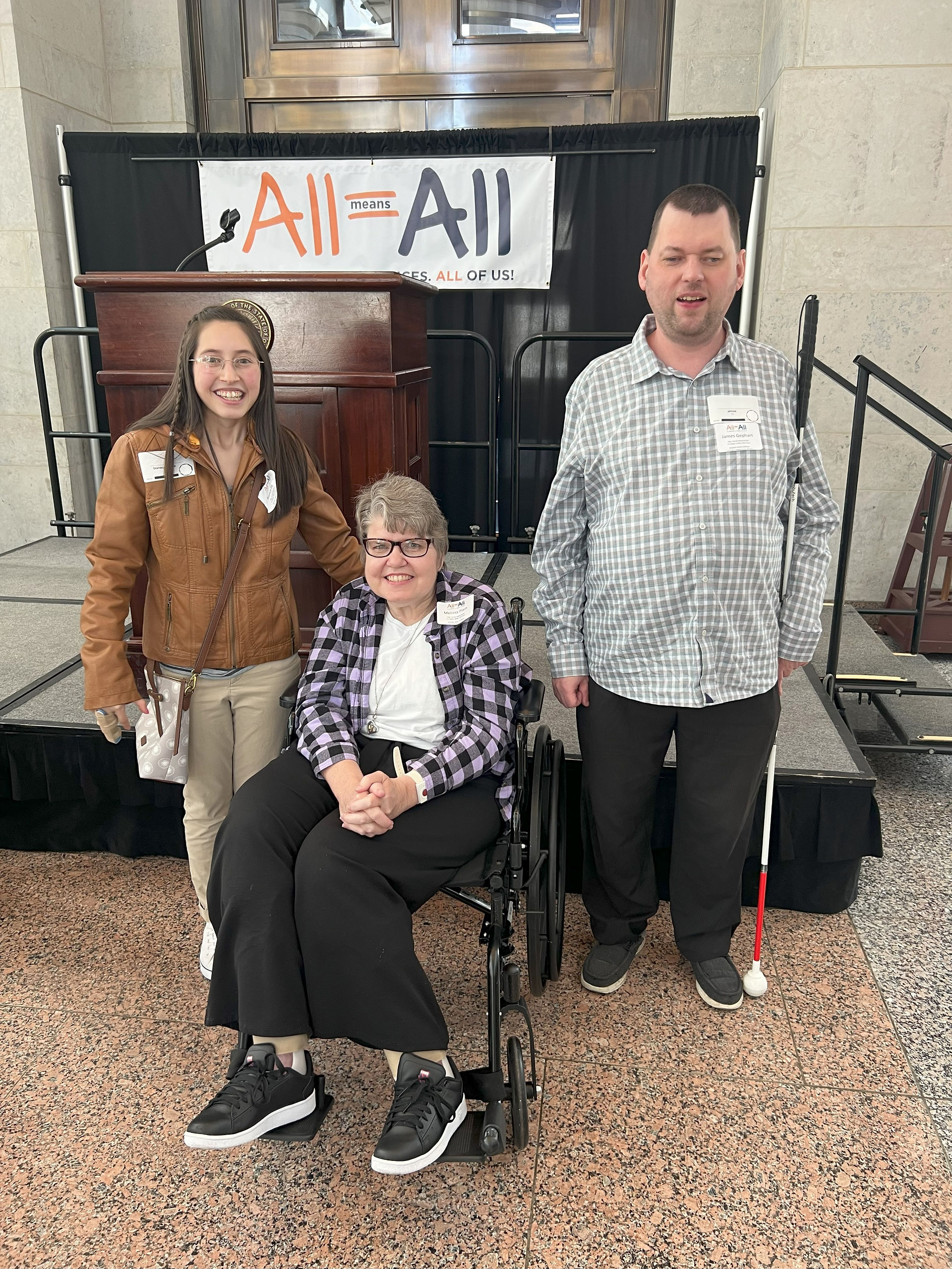 A teenage girl on the left, a woman in wheelchair in the middle, and a man on the right.