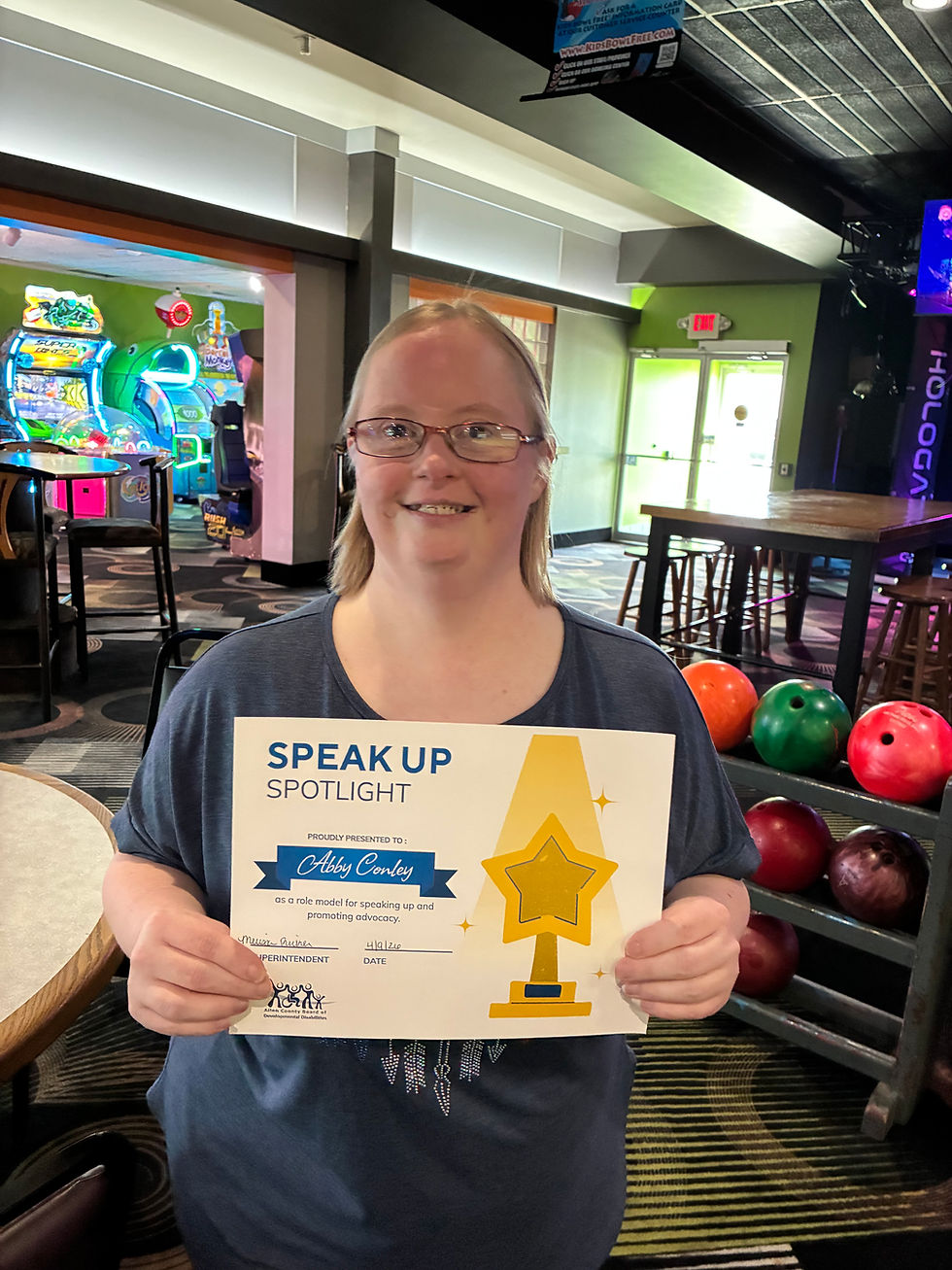 A woman wearing glasses holds up a certificate that says speak up spotlight