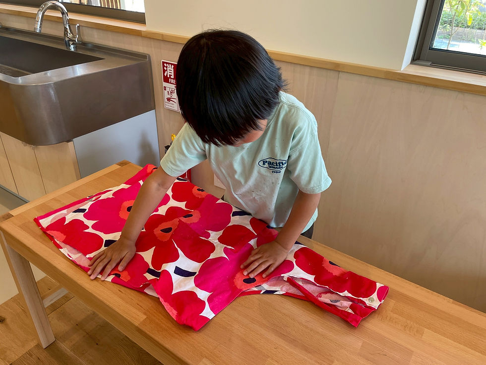 他の人のエプロンを畳んであげている小学生
