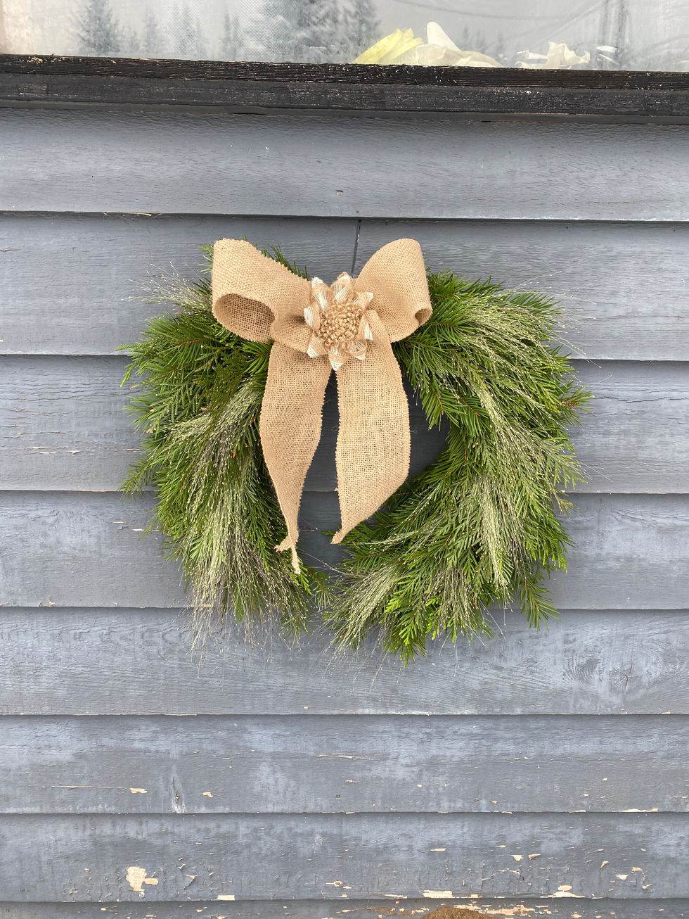 Green pine wreath with burlap bow, Seasonal Wreaths and Swags on grey wall.