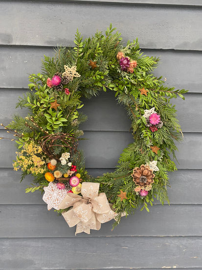 Green wreath, Seasonal Wreaths and Swags, decorated with colorful flowers and bow.