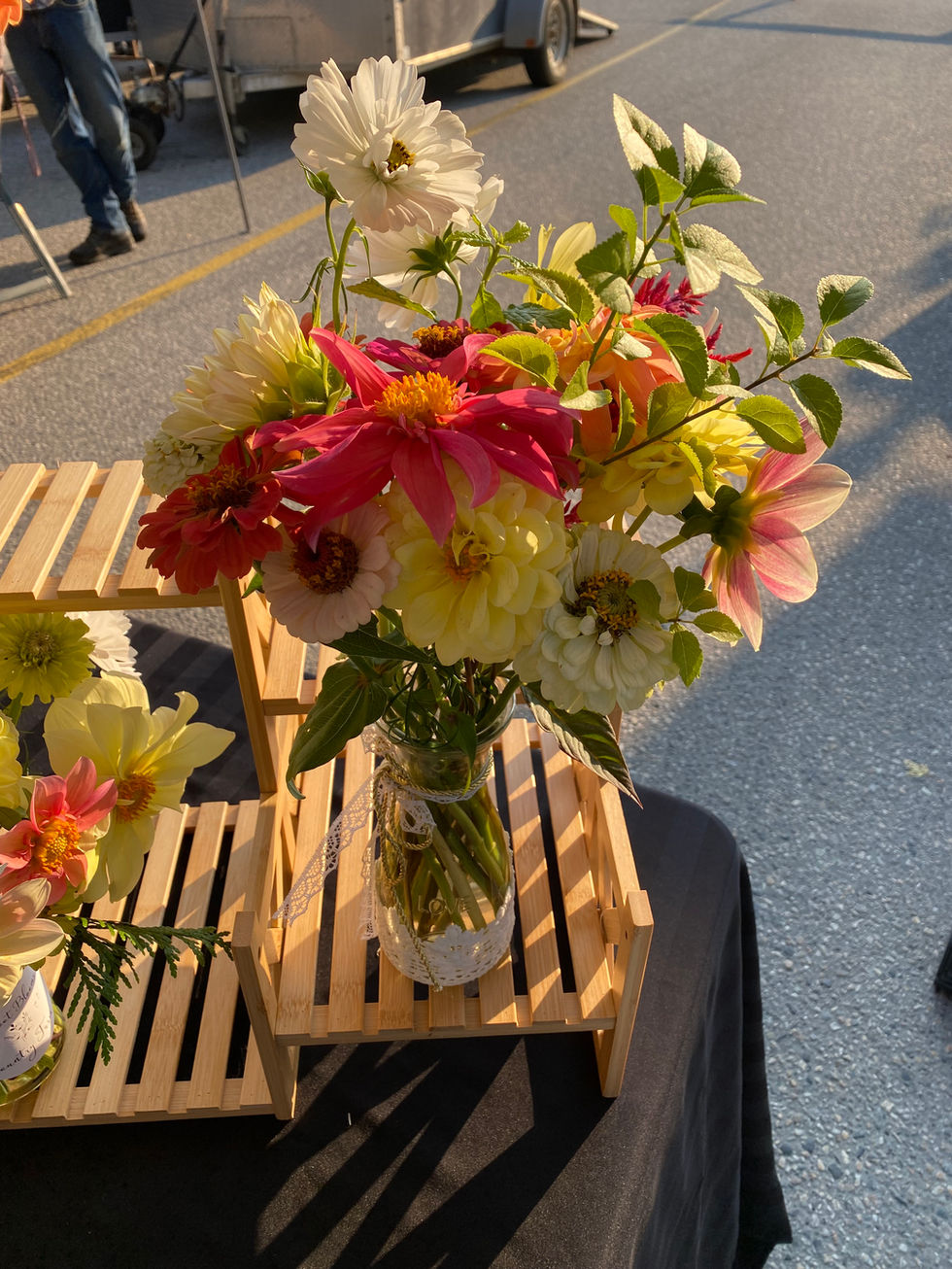 Colorful mixed flower arrangement in jar on wooden market stall.