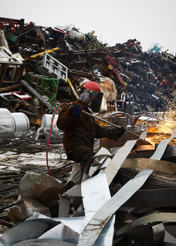 Close-up documentary-plus photo of a worker using a cutting tool on metal, featuring high-contrast sparks and industrial grit.