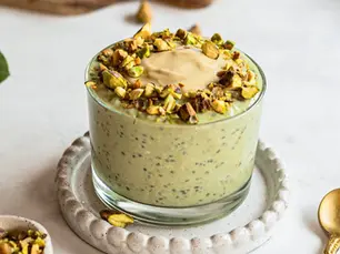 Eine Schüssel mit grünem Matcha und Haferflocken-Mischung wird mit einem Löffel umgerührt, um die Overnight Oats für die antientzündliche Diät vorzubereiten.