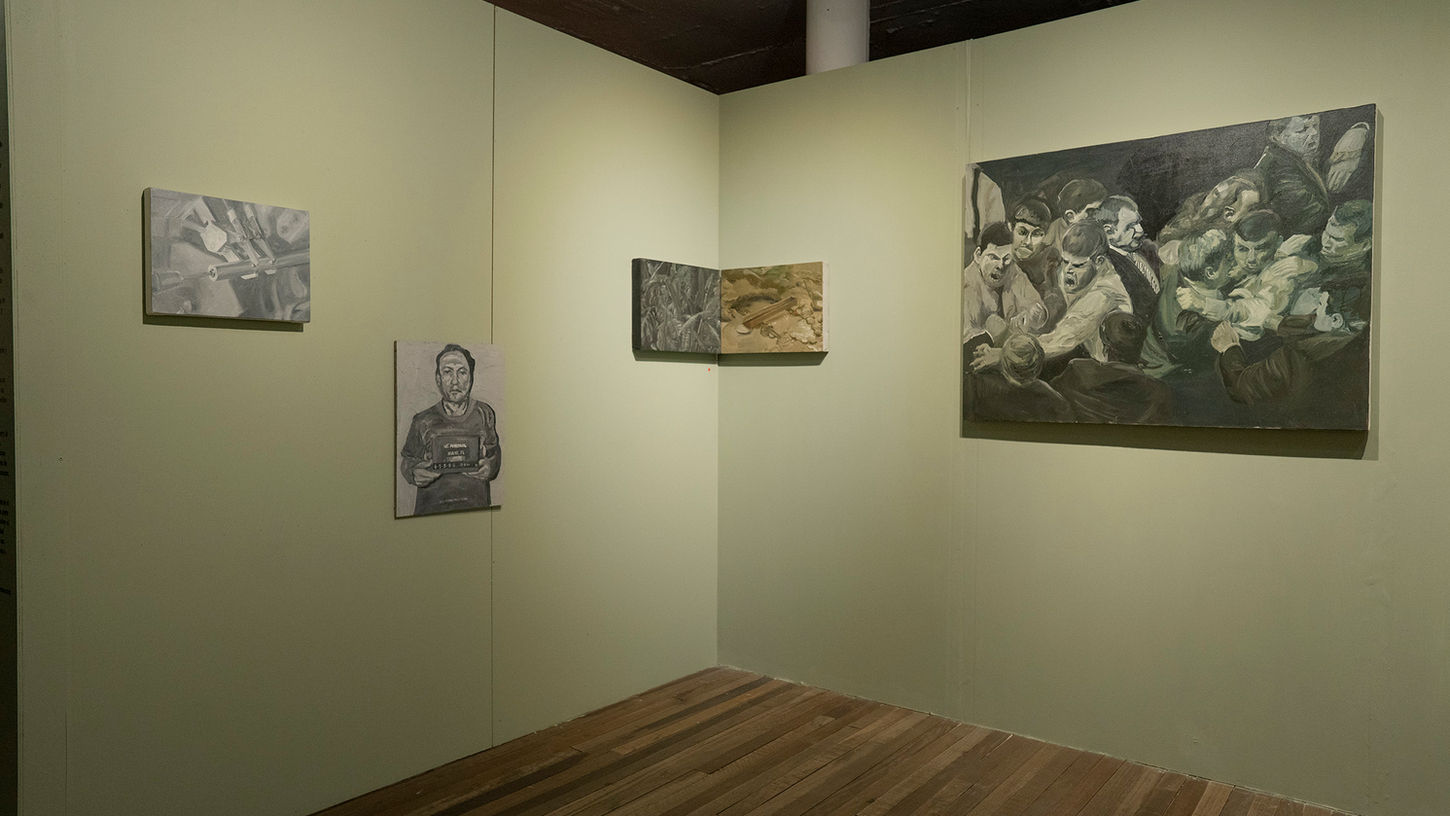 Angled view of a gallery corner showing several framed works spaced across two walls.