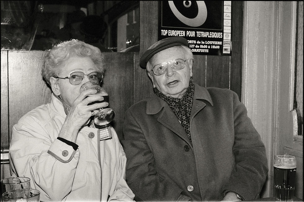 An old couple with glasses on sitting in a pub