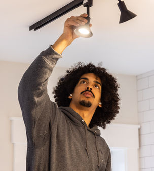 Electrician installing indoor track lighting for a modern kitchen renovation project.