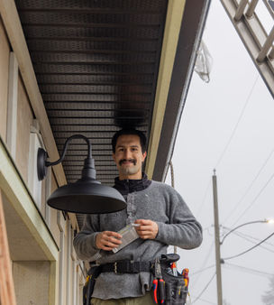 A Four Peaks Power electrician standing on a ladder during a residential lighting maintenance project.