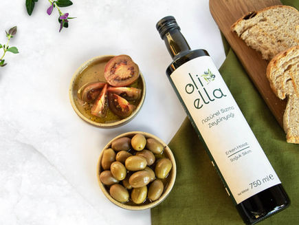 Zeytin, domates ve birkaç dilim ekmeğin yanında bir şişe zeytinyağı duruyor.