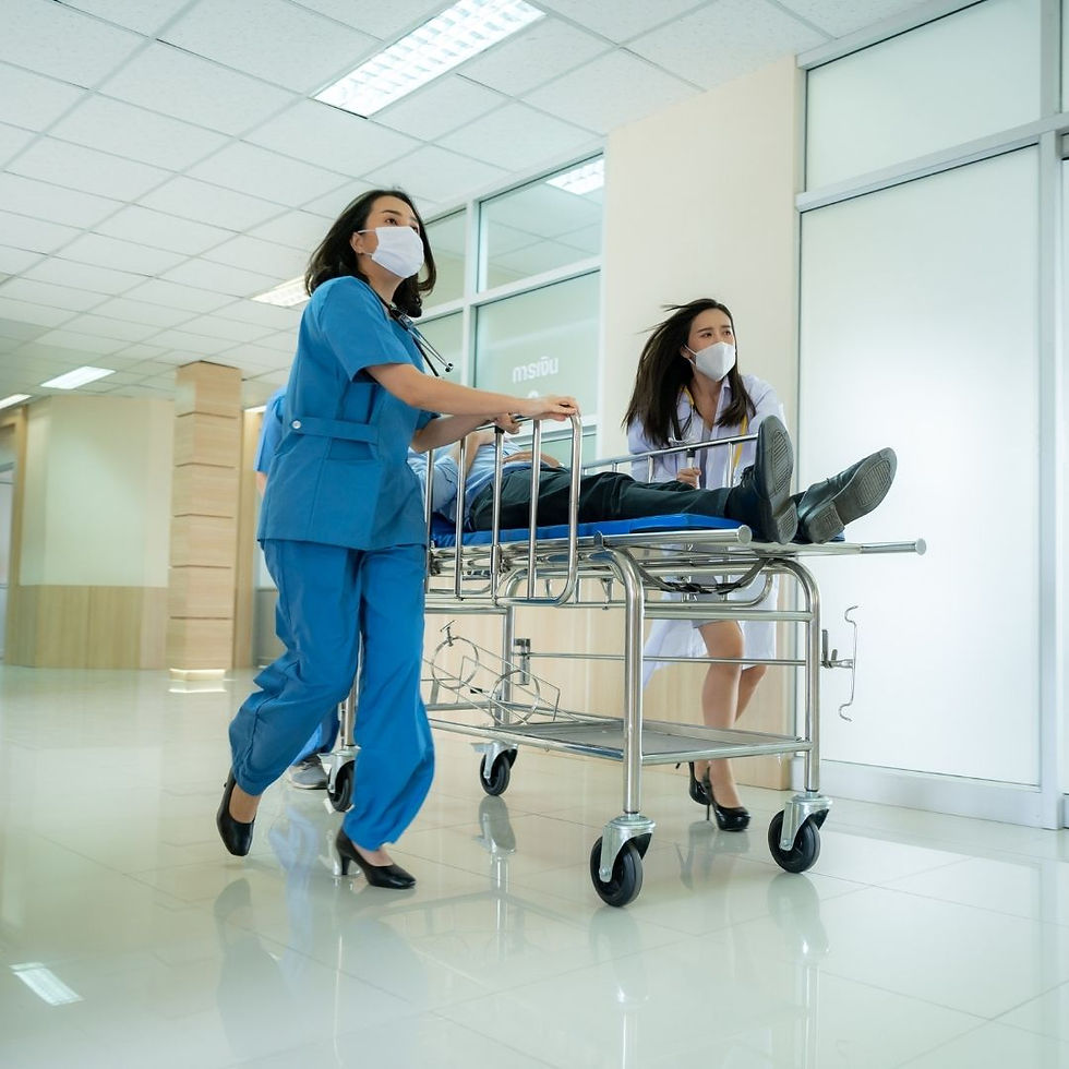 Medical staff in blue and white uniforms urgently push a patient on a stretcher down a hospital hallway. They all wear masks, conveying urgency.