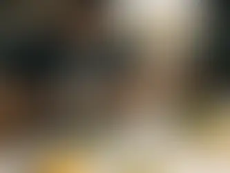 Person in striped apron preparing salad in a kitchen, surrounded by avocado, lime, almond milk, juice, and other ingredients. Sunny setting.