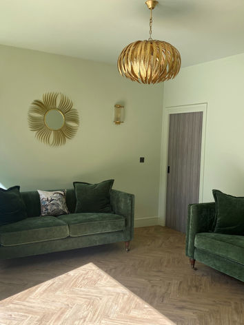 Soft green living room, velvet sofa, gold leaf pendant, painted ceiling, sun mirror