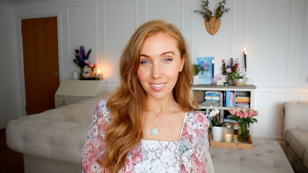 A professional portrait of accredited psychology specialist and Edinburgh Content Creator, Ruth Micallef. She is smiling warmly at the camera, wearing a vintage pink dress in an elegant room filled with candles and flowers.