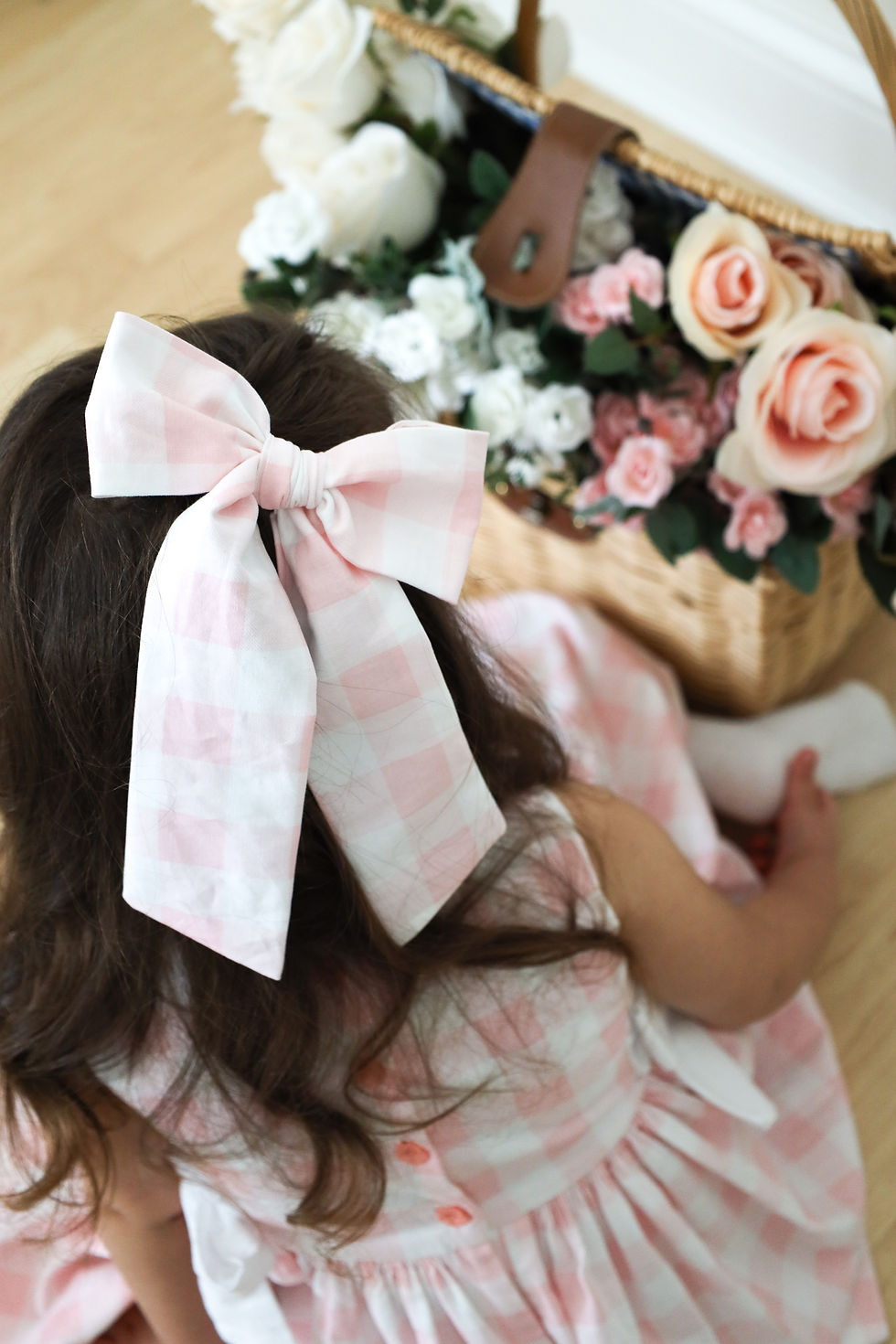 Thumbnail: Girl in a playful plaid dress with bows, delighting in her Easter flower bouquet.