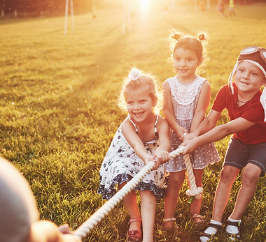 children-play-with-dad-in-the-park-they-pull-the-rope-and-have-fun-laying-on-a-sunny-day.j