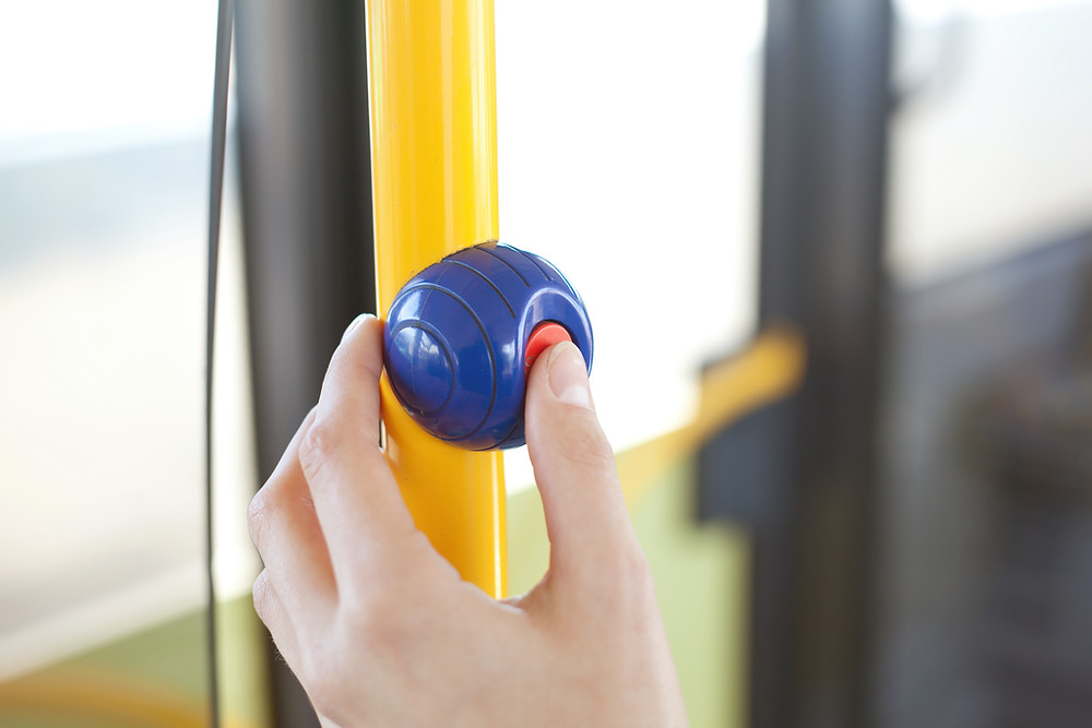 Daumen drückt auf Halteknopf im Bus oder Bahn - hygienisch mit TiTANO-Beschichtung