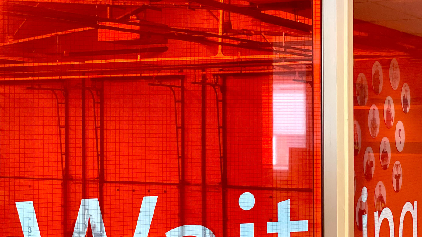 De tekst Waiting op glas geplakt in wachtruimte