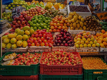 Abundant fruits on a market stall including apples, cherries, lemons, strawberries, mangos, pomegranates