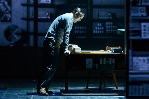 a man leans over a desk with a telephone on it