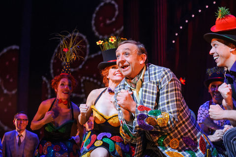 a man in a plaid suit stands next to a woman in a top hat with flowers on it