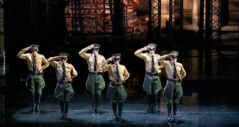 a group of men in military uniforms salute on a stage
