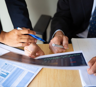 investor-broker-discussing-trading-strategy-holding-papers-with-financial-charts-pens-crop