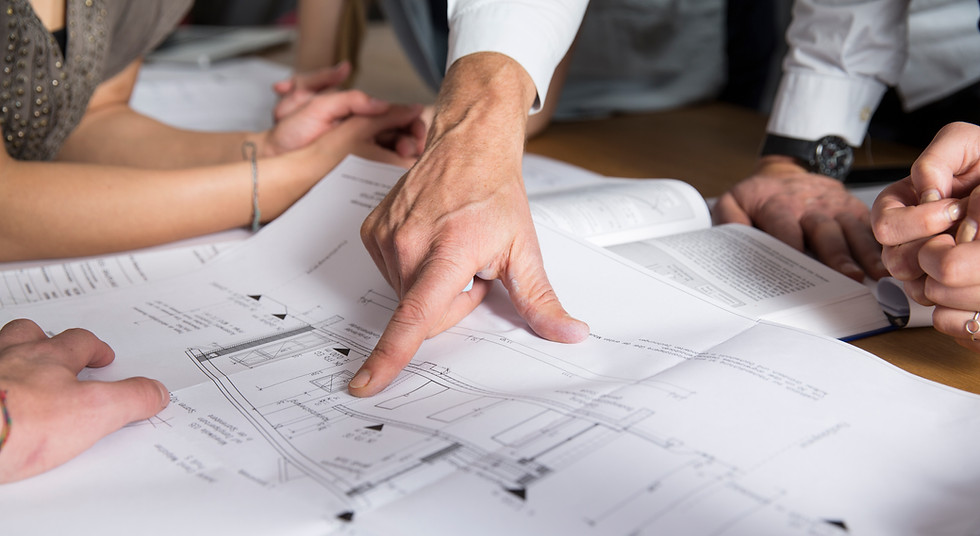 A collaborative team of the client, the architect, and the builder looking over blueprints