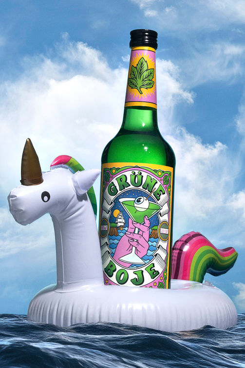 Eien Flasche Grüne Boje Pfefferminzlikör in einem aufblasbaren Einhorn auf dem Wasser mit Himmel als Hintergrund - Beveragefotografie David Weimann