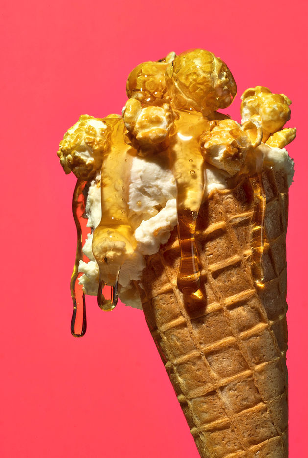 Hochwertige Food-Fotografie: Knuspriges Knalle Popcorn in der Sorte Erdnuss-Karamell auf cremigem Vanilleeis mit goldener Karamellsauce – inszeniert von David Weimann vor farbintensivem pinkem Hintergrund. Foodfotograf Köln Bonn NRW bundesweit