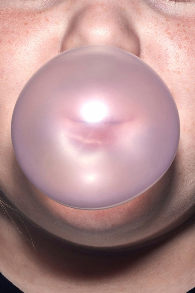 Rosa Kaugummiblase vor dem Gesicht einer Person, schimmernd und glänzend im Licht. Kreative Produktfotografie von David Weimann aus Köln für moderne Markenauftritte in NRW.

