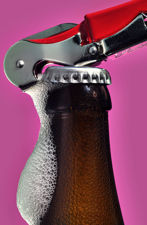 Bierflasche mit Öffner im Close Up. Bierschaum sprudelt die Flasche runter- Foodfotograf david weimann köln bonn deutschland