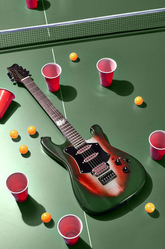 Boutique E-Gitarre mit Sunburst-Finish auf grüner Tischtennisplatte, inszeniert mit Tischtennisbällen und roten Bechern im Studio.