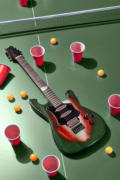 Boutique E-Gitarre mit Sunburst-Finish auf grüner Tischtennisplatte, inszeniert mit Tischtennisbällen und roten Bechern im Studio.