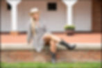 senior portrait of girl wearing boots and long sleeved dress in front of white barn
