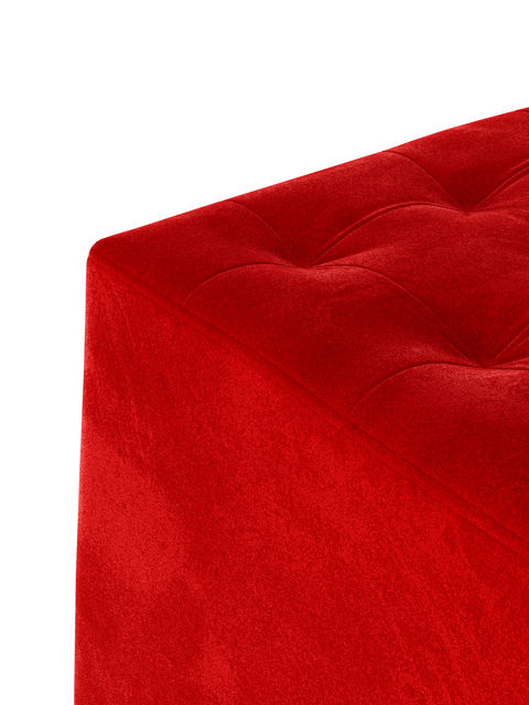 Close-up of a red velvet ottoman cube, showing the plush tufted corner detail.