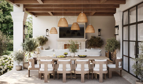 Outdoor dining area with a long wooden table, white cushioned chairs, a fireplace, and pendant lighting under a wooden pergola.