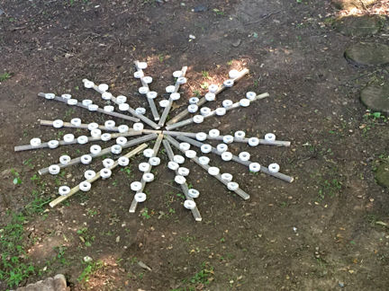 unpainted-Auntie-Caryl's-spirit-sticks-laying-in-a-wagon-wheel-formation-on-the-ground-spring-2021-Clinton-Maryland-USA