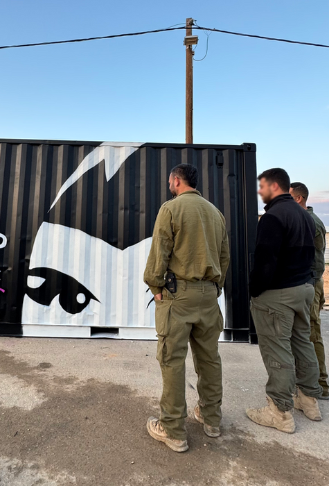 חיילים ליד גרפיטי על קיר: 'כולה עלייך'