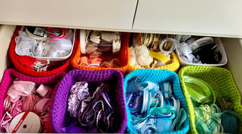 an open drawer of coloured baskets in rainbow order, each basket houses the same coloured ribbons inside